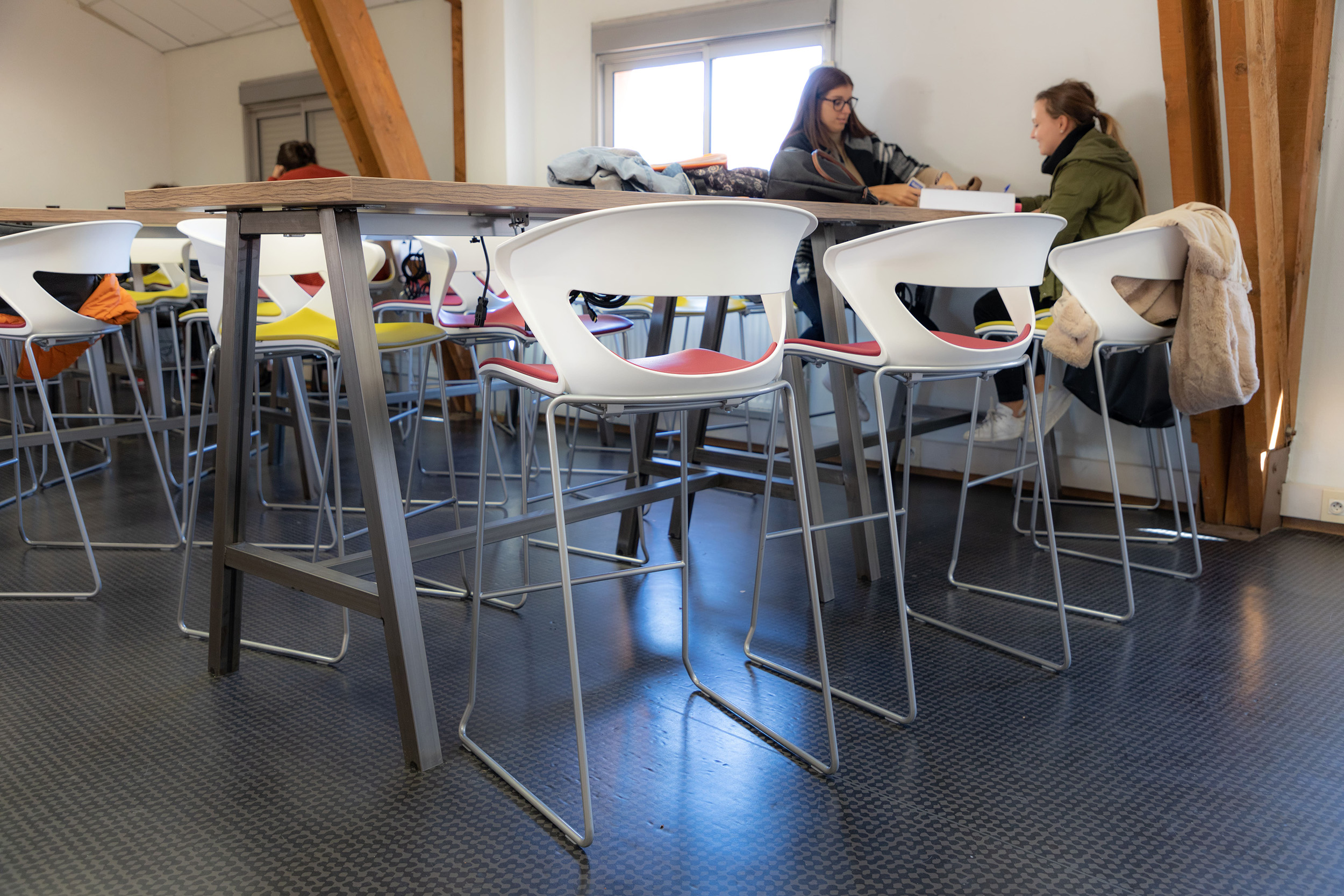 Tabouret avec assise rembourrée et tables hautes dans une salle de pause dans un établissement scolaire en Isère